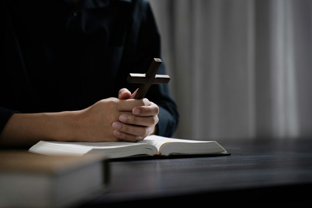 Closeup of simple wooden Christian cross on Bible. Concept of hope, faith, christianity, religion.